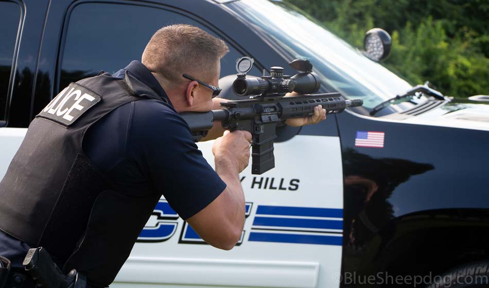Police Sniper Ammunition - In this photo, we see a SWAT police officer firing an AR-10 style rifle using his patrol car for cover. This was part of testing to identify which sniper bullets performed best for accuracy and penetration.